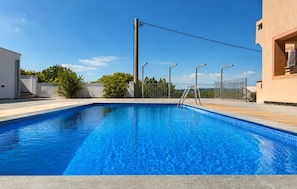 Ein rechteckiger Swimmingpool mit klarem, blauem Wasser, umgeben von einer gefliesten Liegefläche.