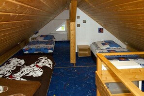 Ein kleines Schlafzimmer im Dachgeschoss mit zwei Betten, einer Holzbalkendecke und einem Fenster.