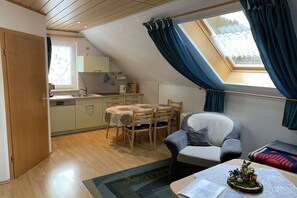 Ein Loft-Zimmer mit Esstisch, einer Couch, einem Fenster mit Vorhängen und einem Oberlicht.