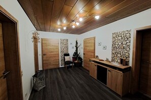 Ein Zimmer mit Holzboden, Deckenbalken und einer Wand im Blockhausstil.