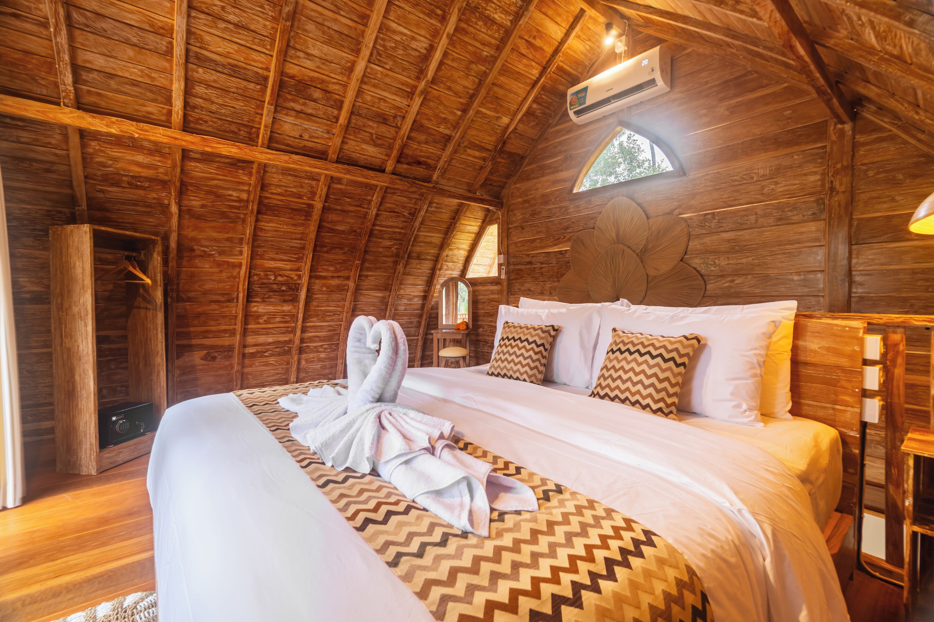 A wooden cabin-style room with a bed, a hanging light fixture, and a small table.