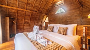 A wooden cabin-style room with a bed, a hanging light fixture, and a small table.