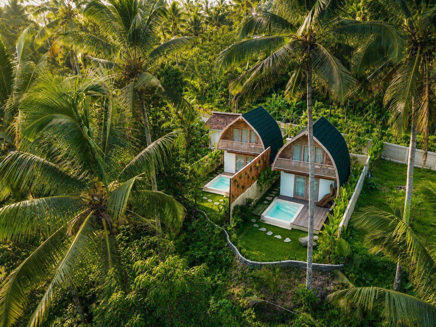 Two bungalow-style accommodations with curved roofs, each featuring a private pool and surrounded by lush tropical vegetation.
