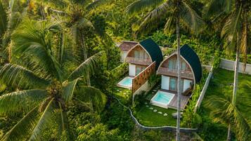 Two bungalow-style accommodations with curved roofs, each featuring a private pool and surrounded by lush tropical vegetation.