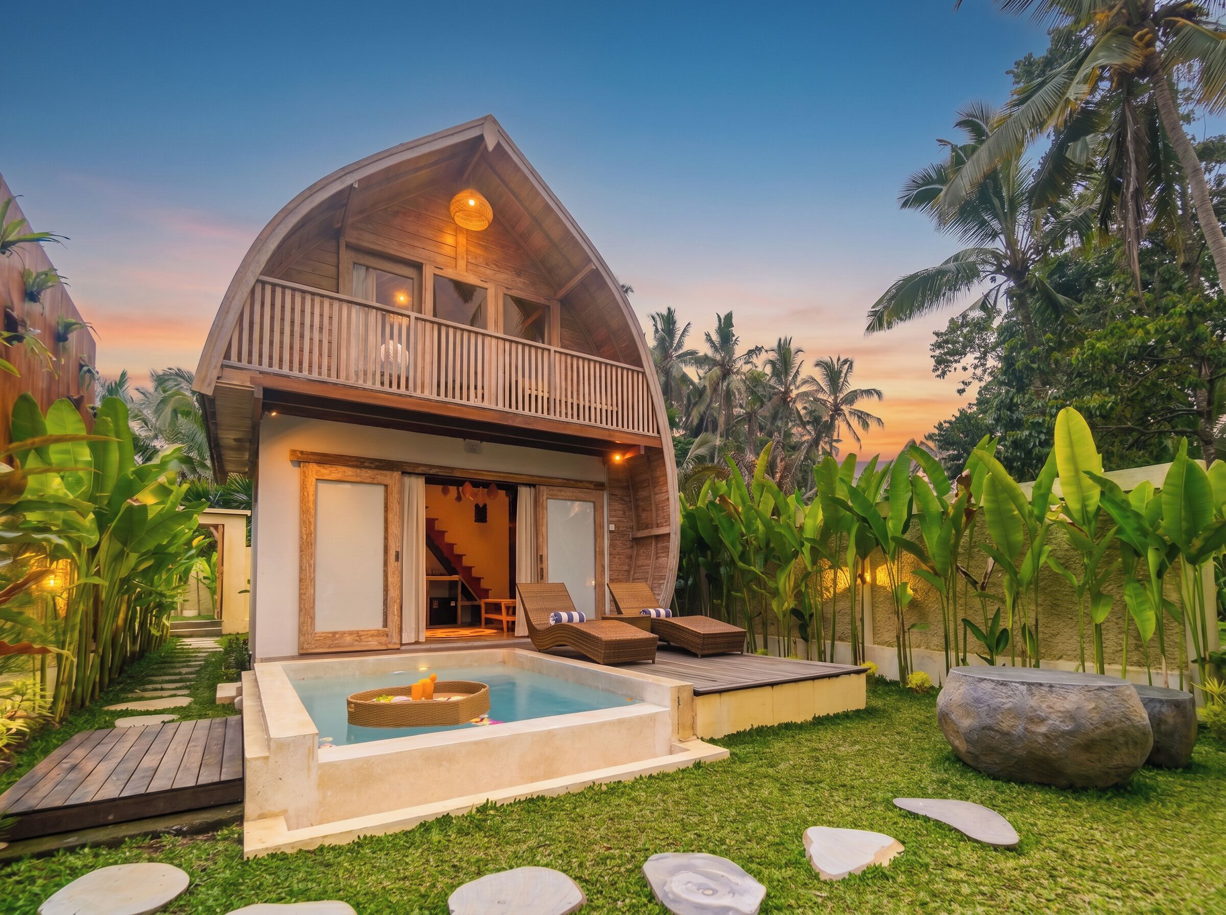 A two-story house with a balcony, a swimming pool, and tropical vegetation.