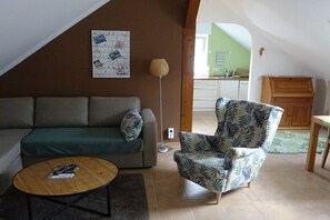 Ein Wohnzimmer mit einer Couch, Sesseln, einem Couchtisch und einer Wand mit Fotos.