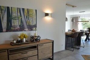 Eine moderne Küche mit Essbereich, einem großen Wandbild zum Thema Wald und einem Holzkonsolentisch mit Dekoration.
