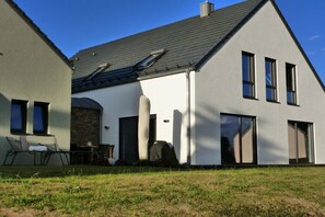 Ein modernes, zweistöckiges Haus mit geneigtem Dach, großen Fenstern und einer sichtbaren Garagentür.