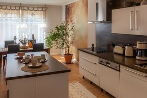 A modern kitchen with a central island, a dining area with a table and chairs, and a large potted plant. - Holiday apartment with 2 bedrooms (Zittau)