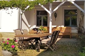 Ein Essbereich im Freien mit Tisch, Stühlen, einer Holzbank und einem Blumentopf.