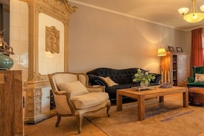 Ein Wohnzimmer mit einem dunklen Sofa, einem hellen Sessel, einem Holztisch und einer dekorativen Vase.
