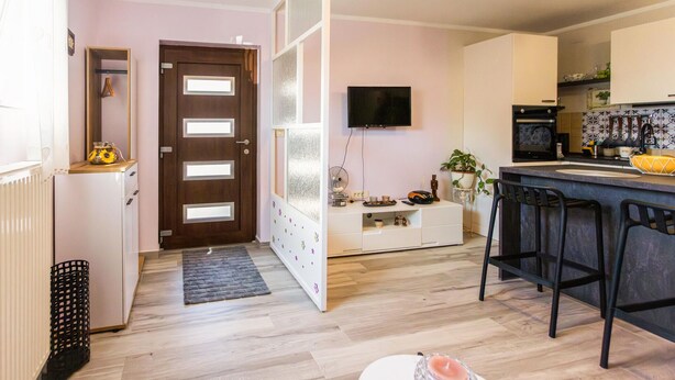 A modern kitchen with a TV, a refrigerator, and a dining area with bar stools. - Nice apartment in Krasica with WiFi (Krasica)