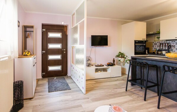 A modern kitchen with a TV, a refrigerator, and a dining area with bar stools. - Nice apartment in Krasica with WiFi (Krasica)