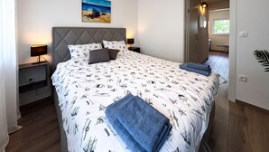 A bedroom with a bed, nightstands, a headboard, a painting, and a door leading to another room. - 2 bedroom awesome home in Jadranovo (Jadranovo)