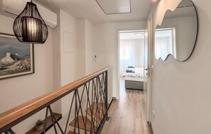 Ein Flur mit Holzbalkon, einem Gemälde, einem Spiegel und einem Bett im Hintergrund.
