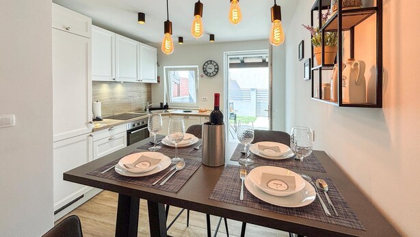 A dining area with a table set for four, a wine bottle, and a clock on the wall. - 2 bedroom awesome home in Jadranovo (Jadranovo)