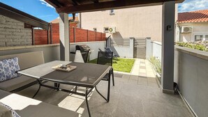 A covered patio with a table and chairs, a grill, and a small lawn. - 2 bedroom awesome home in Jadranovo (Jadranovo)