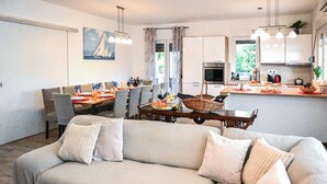 Een moderne woonkamer met een bank, eethoek, keuken en kunst aan de muur.
