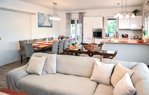 A modern living room with a sofa, dining area, kitchen, and artwork on the wall. - Awesome home in Dobrinj (Dobrinj)