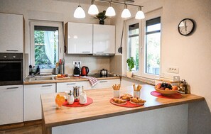 A modern kitchen with white cabinets, a wooden countertop, a kettle, a coffee maker, and a clock on the wall. - Awesome home in Dobrinj (Dobrinj)