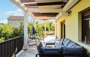 A covered outdoor seating area with a sofa and chairs, a small table, and a hanging chair. - Awesome home in Dobrinj (Dobrinj)