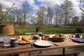 An outdoor dining table with various food items and utensils. - Holiday home in Bugewitz with swimming pool (Bugewitz)
