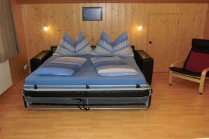 A room with a bed, two bedside tables, a chair, and wooden walls. - Holiday apartment with 2 bedrooms (Hasliberg Goldern)
