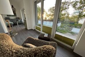 Ein modernes Wohnzimmer mit großem Fenster, einer Couch, einem Couchtisch und einer Lampe.