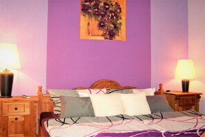 Ein Schlafzimmer mit einem Bett, zwei Nachttischen, einer Ablagefläche und einer Lampe auf jedem Tisch.