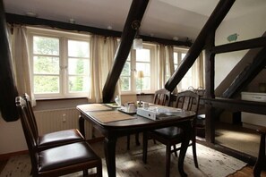 Ein Essbereich mit Tisch, Stühlen und einem Fenster mit Vorhängen.