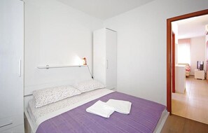 Ein Schlafzimmer mit Bett, Kleiderschrank, Schreibtisch mit Stuhl und Fernseher.