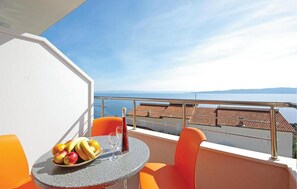 Ein Balkon mit einem Tisch, orangefarbenen Stühlen und einer Obstschale.