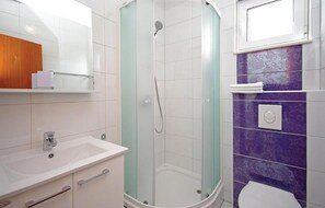 Ein Badezimmer mit Dusche, Waschbecken, Toilette und Spiegel.