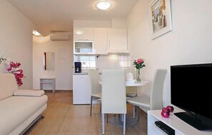 Ein kompakter Wohnbereich mit Küchenzeile, Essbereich, Sofa und Fernseher.