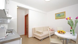 Una cucina moderna con zona pranzo, divano e tavolo con frutta e fiori.