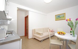 A modern kitchen with a dining area, a sofa, and a table with fruit and flowers. - Awesome apartment in Brela with swimming pool (Brela)
