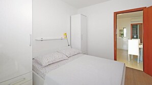 A bedroom with a bed, a bedside table, a wardrobe, and a door leading to a bathroom. - Lovely apartment in Brela with WiFi (Brela)