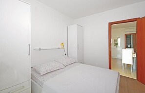 Ein Schlafzimmer mit einem Bett, einem Nachttisch, einem Kleiderschrank und einer Tür zu einem Badezimmer.
