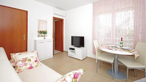 A living room with a sofa, TV, dining table, and chairs. - Lovely apartment in Brela with WiFi (Brela)
