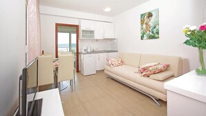 A modern apartment with a kitchenette, a dining area, a sofa with floral cushions, and a painting on the wall. - Lovely apartment in Brela with WiFi (Brela)