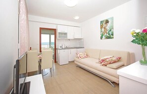 Ein modernes Apartment mit Küchenzeile, Essbereich, einer Couch mit floralen Kissen und einem Bild an der Wand.
