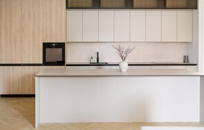 A modern kitchen with a central island, wooden cabinets, and a built-in oven. - Beautiful home in Donji Prolozac (Donji Prolozac)