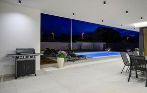 A modern outdoor patio with a pool, a grill, and lounge chairs. - Beautiful home in Donji Prolozac (Donji Prolozac)