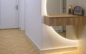 A modern interior with a wooden console table, a wall-mounted clock, and a door with a geometric pattern. - Beautiful home in Donji Prolozac (Donji Prolozac)