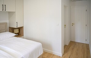 Una camera da letto con un letto, un comodino, una lampada e una porta.
