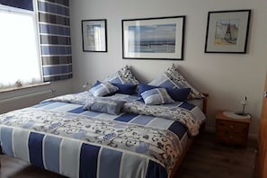 Ein Schlafzimmer mit einem Bett, einem Nachttisch und drei gerahmten Bildern an der Wand.