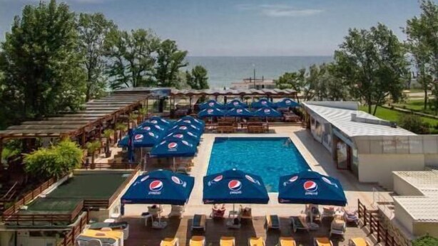 Area piscina con ombrelloni, lettini e vista sul mare.