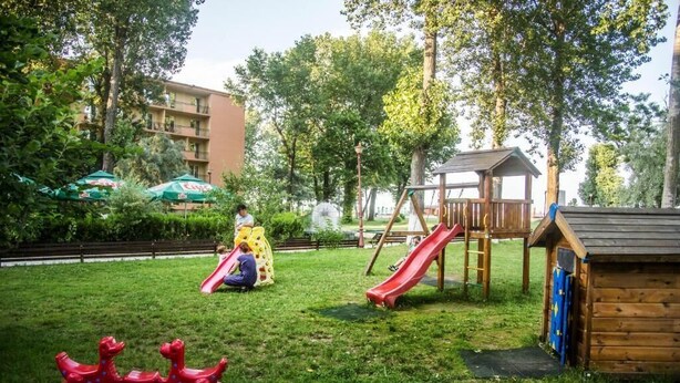 A playground with a slide, a swing set, and a small wooden structure. - Hotel Central (Mamaia)