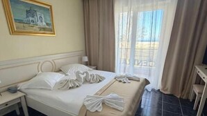 Una camera d'albergo con un letto, un comodino, una scrivania e una finestra con tende.