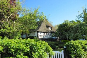 A traditional thatched-roof house surrounded by lush greenery. - Bender Grinding Shops (Ulsnis)